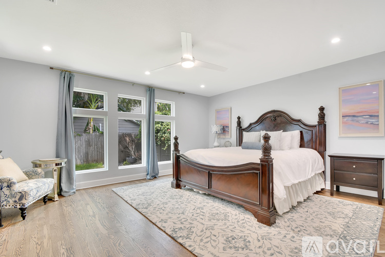 A bedroom with a large bed, a dresser, and a window with curtains.