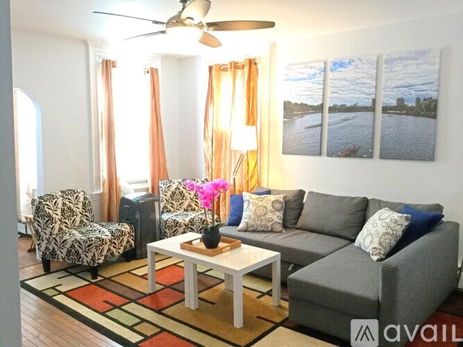 A living room with a grey couch, a coffee table, and a fan.