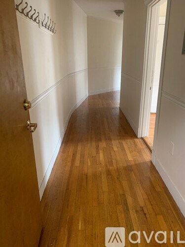 A hallway with wood flooring and white walls.