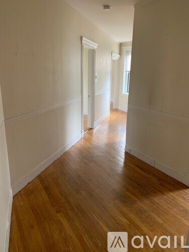 A hallway with wooden floors and white walls.