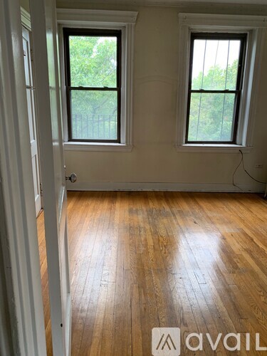 A room with wooden floors and two windows.