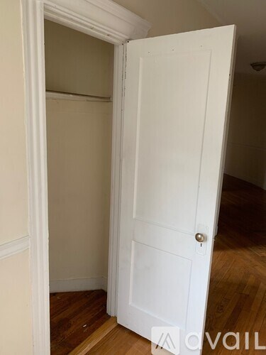A white door is open to a room with wooden floors.