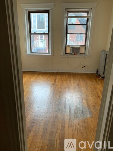 A room with wooden floors and two windows.