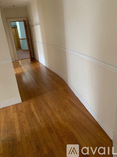 A hallway with wooden floors and white walls.