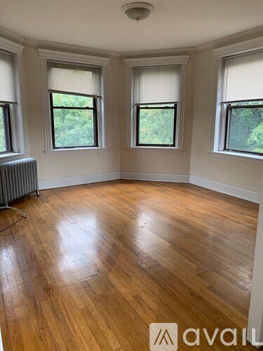 A room with wooden floors and three windows.