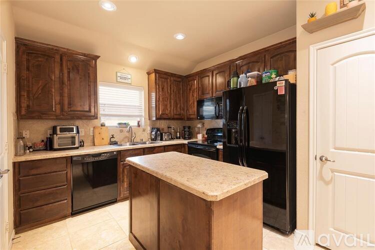 A kitchen with wooden cabinets and a black refrigerator.