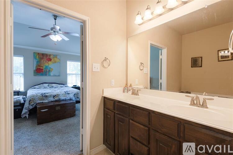 A bathroom with a mirror, sink, and a bedroom visible through the door.