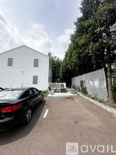 A black car is parked in a parking lot in front of a white building.