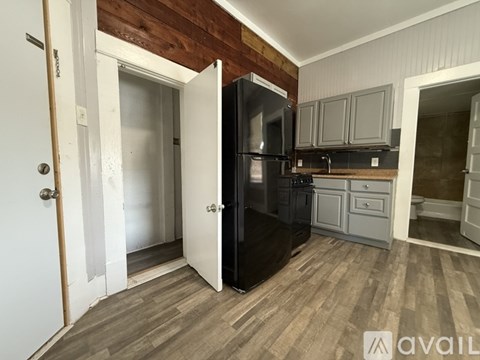 A kitchen with a black refrigerator and wooden cabinets.