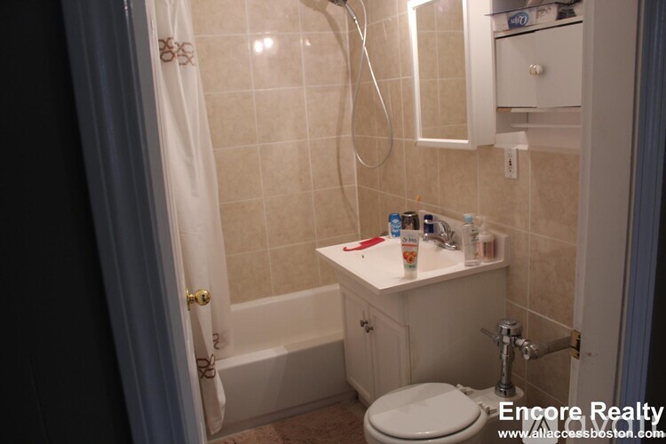 A white bathroom with a toilet, sink, and shower.