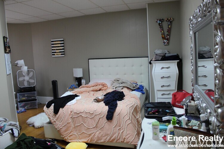 A bedroom with a messy bed and a dresser with a mirror.
