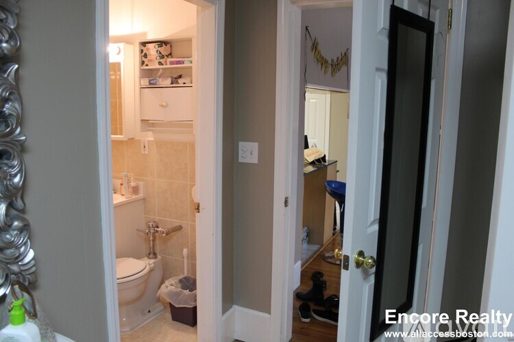 A bathroom with a toilet, sink, and mirror.