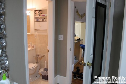 A bathroom with a toilet, sink, and mirror.