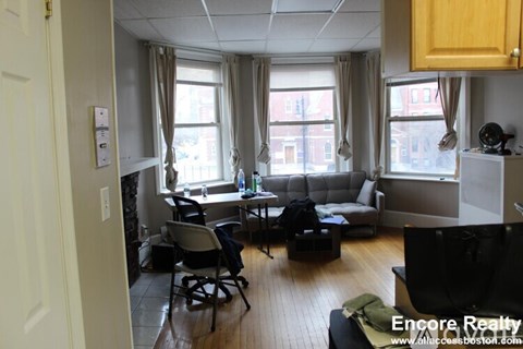 A living room with a couch, chairs, and a television.