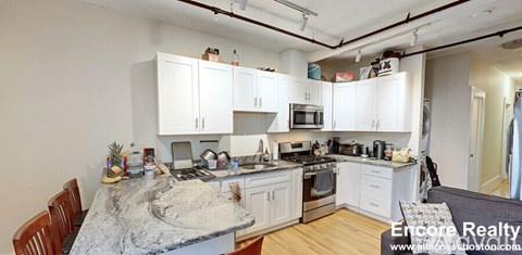 A kitchen with white cabinets and a granite countertop.
