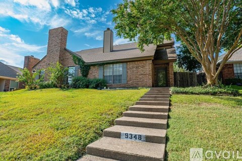 A house with a brick facade and a tree in front.