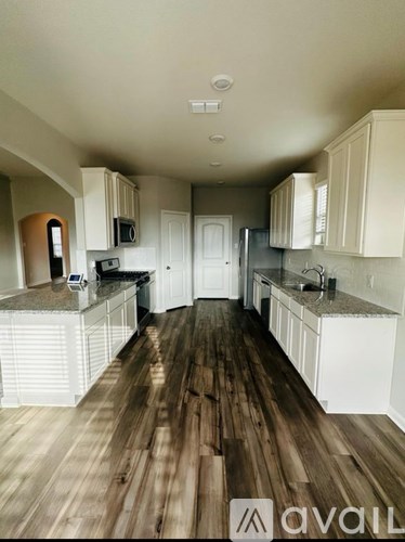 A kitchen with white cabinets and a wooden floor.