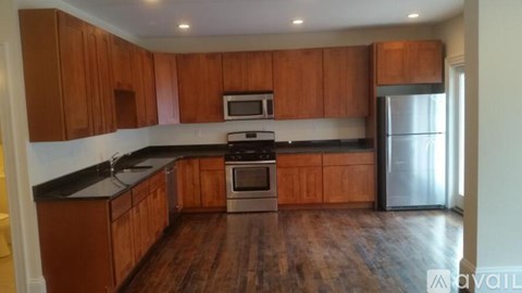 A kitchen with wooden cabinets and a stainless steel refrigerator.