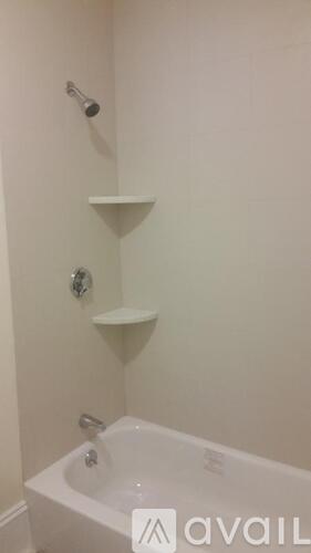 A white bathroom with a bathtub and a shower head.