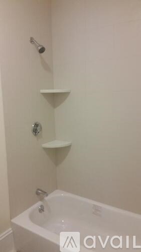 A white bathroom with a bathtub and a shower head.