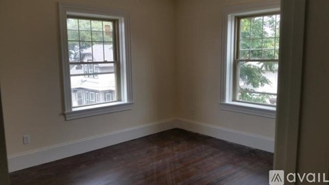 A room with two windows and wooden flooring.