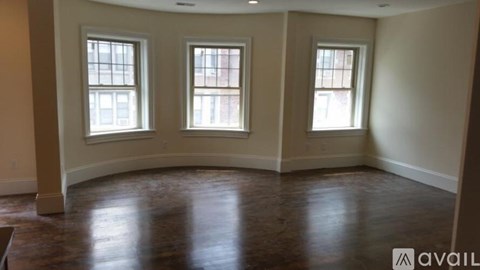 A room with wooden floors and three windows.