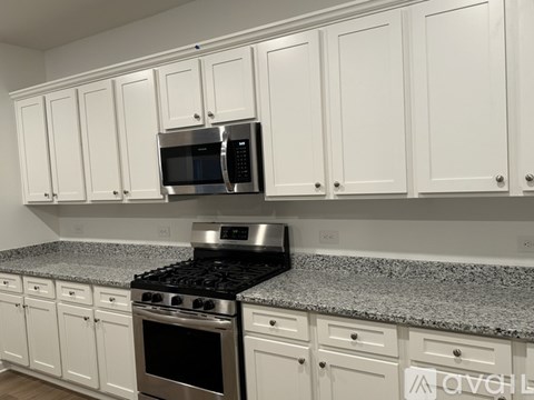 A kitchen with white cabinets and a granite countertop.