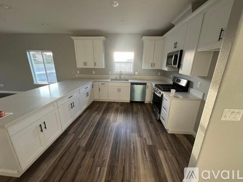 A kitchen with white cabinets and a wooden floor.