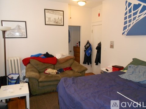 A small bedroom with a bed, a couch, and a table.