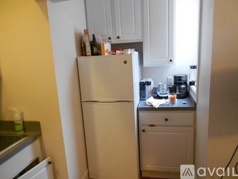 A white refrigerator in a kitchen with a countertop and cabinets.