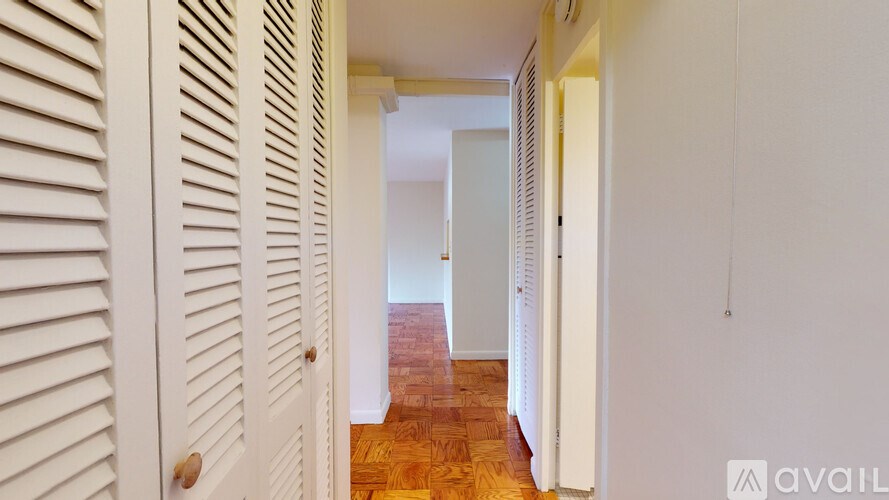 A hallway with white walls and a wooden floor.
