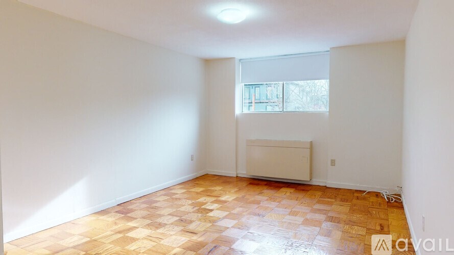 A room with a wooden floor and a window with blinds.