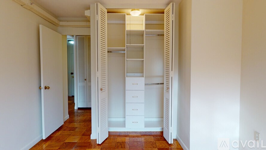 A white closet with drawers and shelves is open.