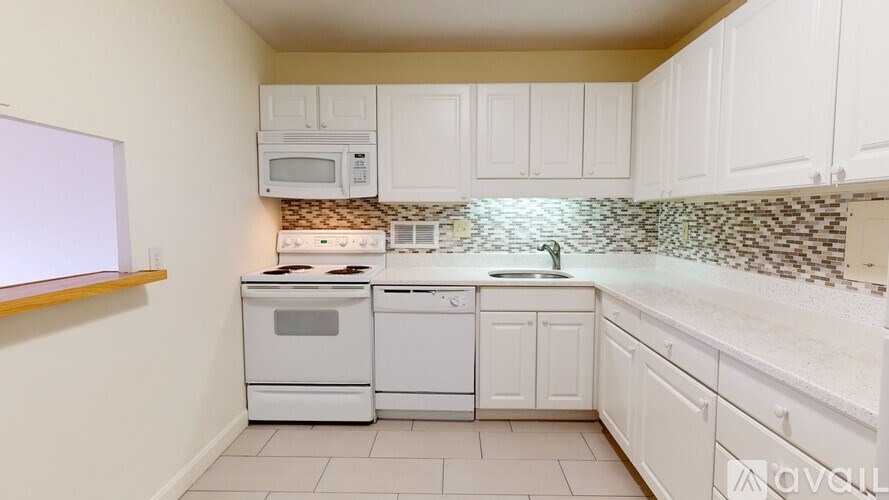 A kitchen with white cabinets and a tiled backsplash.