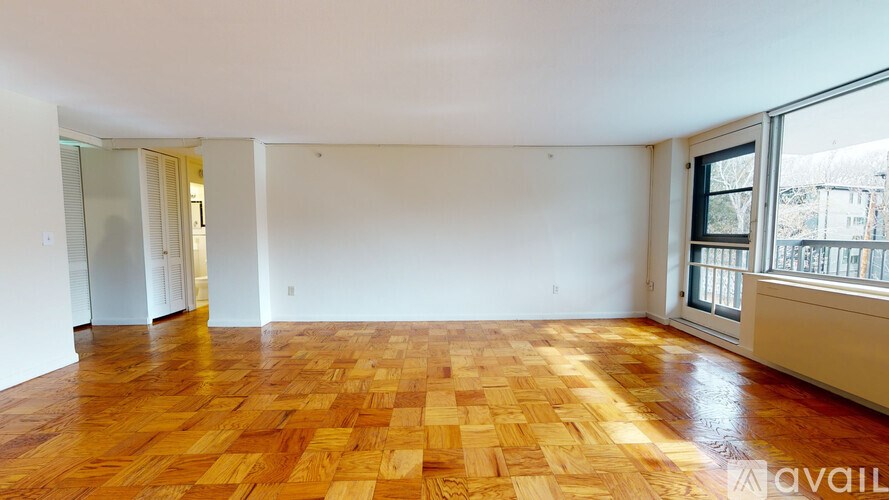 A room with wooden flooring and a window on the right side.