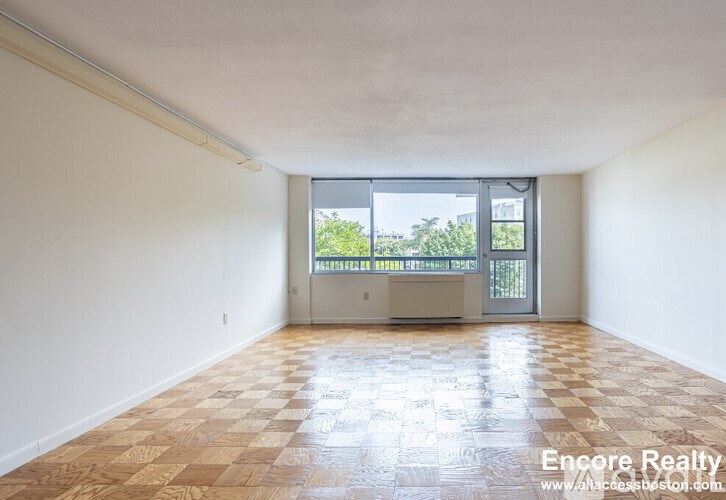 A room with a checkered floor and a sliding glass door leading to a balcony.