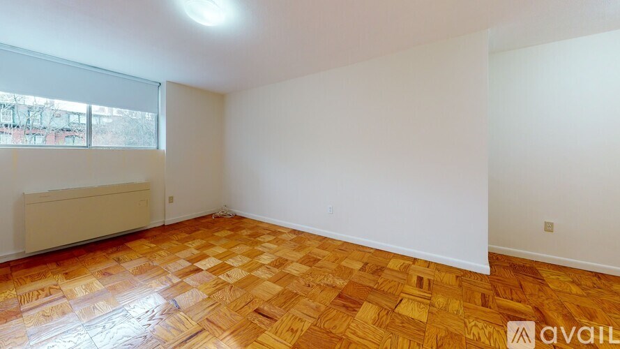 A room with wooden flooring and a window with blinds.