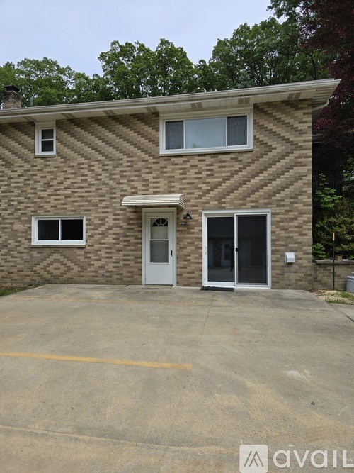 A house with a white door and windows with a brown brick wall.