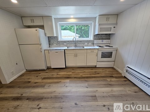 A kitchen with white appliances and wooden floors.