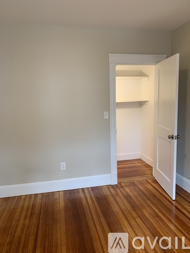 A room with a white door and wooden flooring.