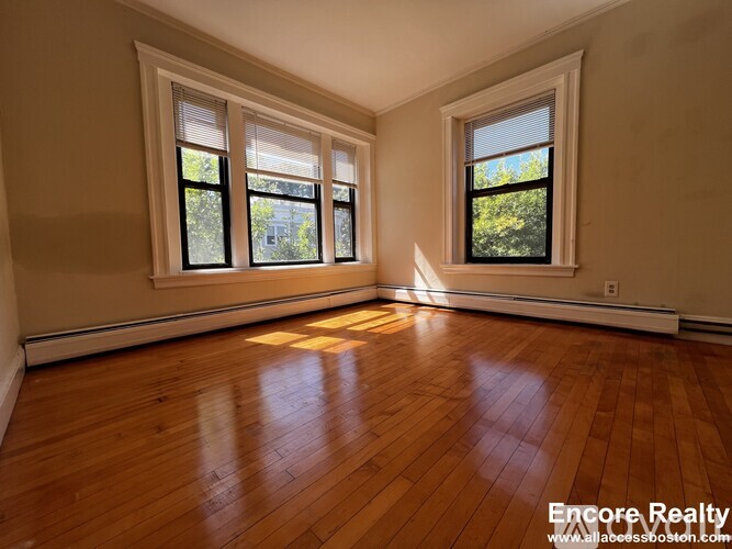 A room with wooden floors and two windows.