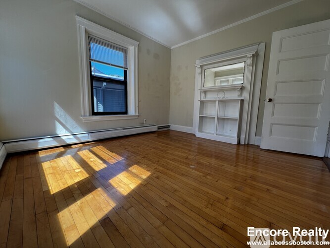 A room with wooden floors and a window letting in sunlight.