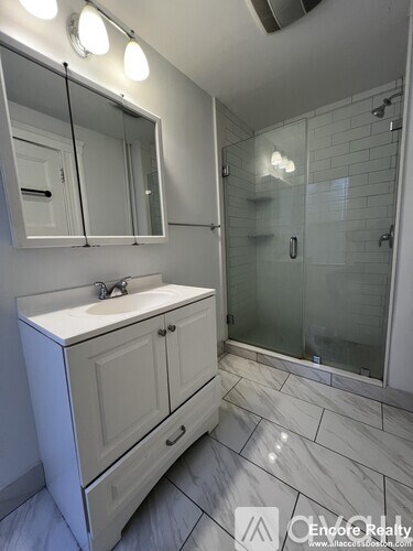 A bathroom with a sink, mirror, and shower.