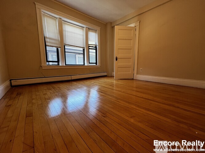 A room with wooden floors and a door leading to another room.