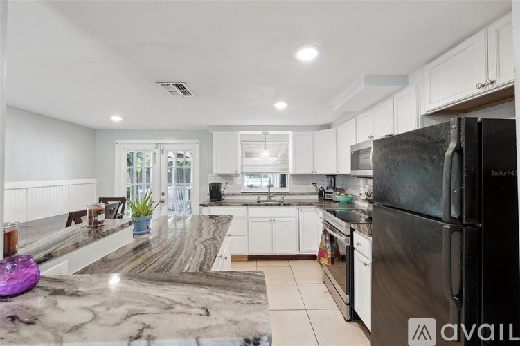 A kitchen with a black refrigerator and white cabinets.