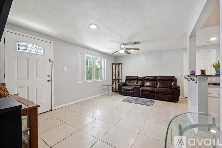 A living room with a brown leather couch and a ceiling fan.