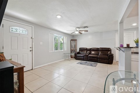 A living room with a brown leather couch and a ceiling fan.