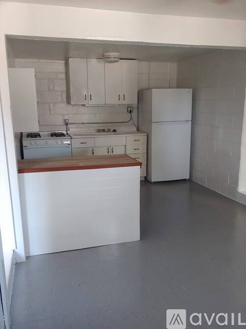 A kitchen with white cabinets and a white fridge.