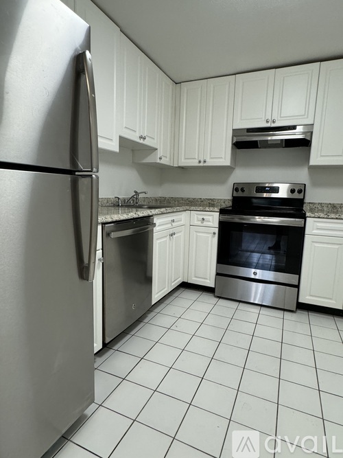 A kitchen with white cabinets and a stainless steel refrigerator.
