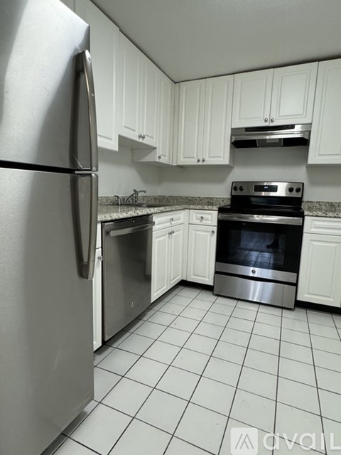 A kitchen with white cabinets and a stainless steel refrigerator.